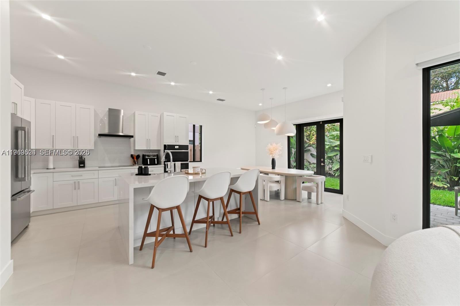 7771 Southwest 99th Street Miami, FL 33156 - Photo 11 of 33 a kitchen with a dining table chairs and white cabinets