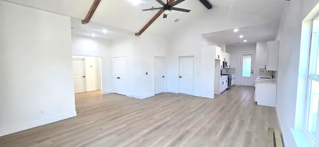 a view of a big room with wooden floor windows and a ceiling fan