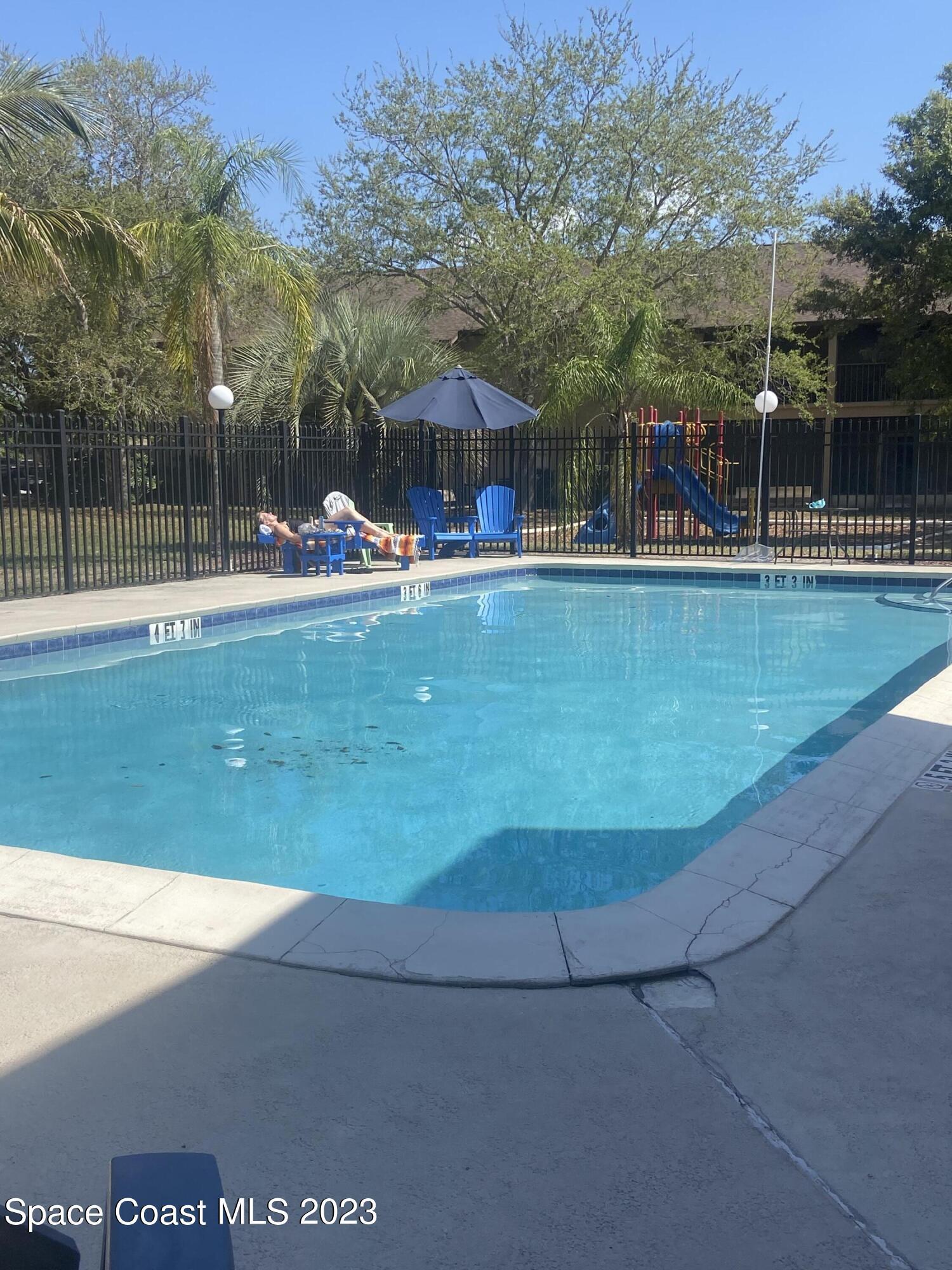 290 Spring Drive, Unit 4 Merritt Island, FL 32953 - Photo 2 of 16 a view of a swimming pool with a table and chairs
