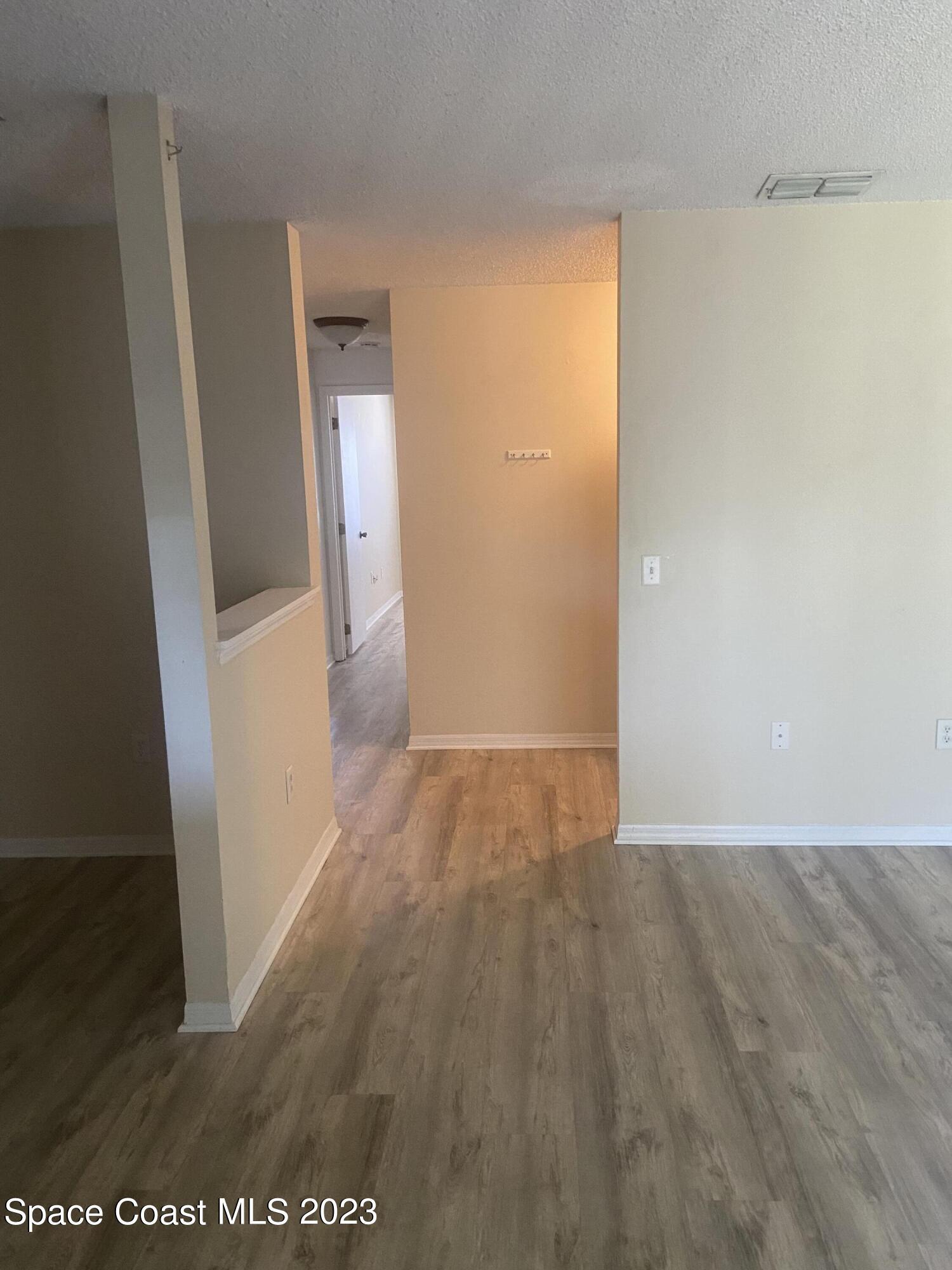 290 Spring Drive, Unit 4 Merritt Island, FL 32953 - Photo 7 of 16 an empty room with wooden floor and a bathroom