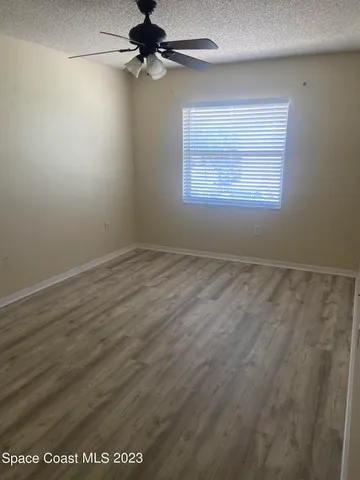 an empty room with a window and a ceiling fan