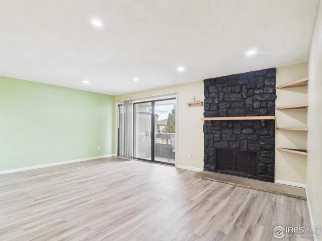 an empty room with wooden floor fireplace and windows