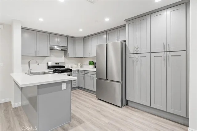 a kitchen with stainless steel appliances granite countertop a refrigerator sink and white cabinets