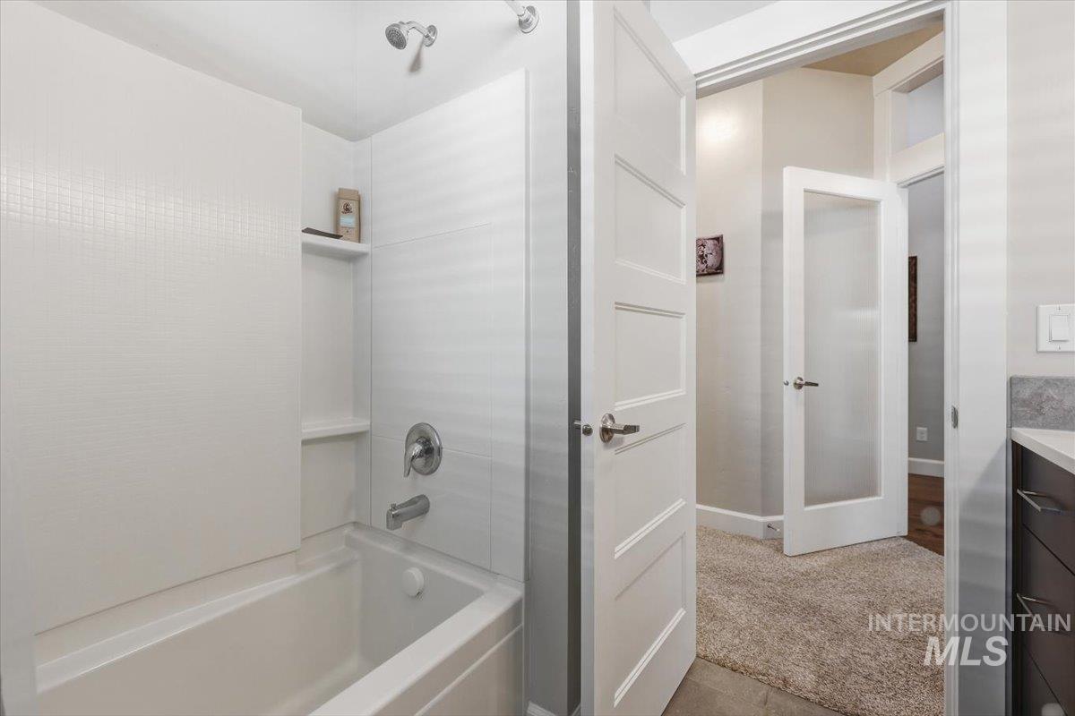1303 West Brando Street Meridian, ID 83646 - Photo 8 of 49 Enclosed tub and shower combination with white tile surround and recessed shelving