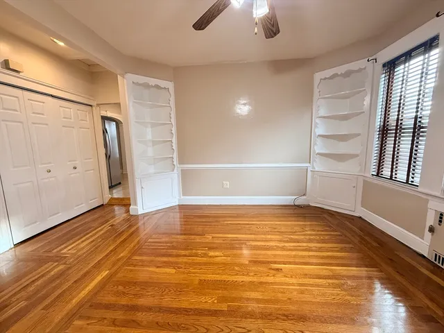 a view of an empty room with window and wooden floor