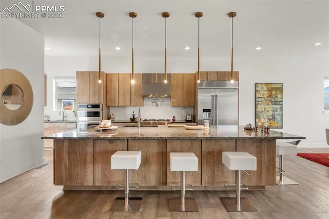 a kitchen with kitchen island stainless steel appliances a table chairs sink and window