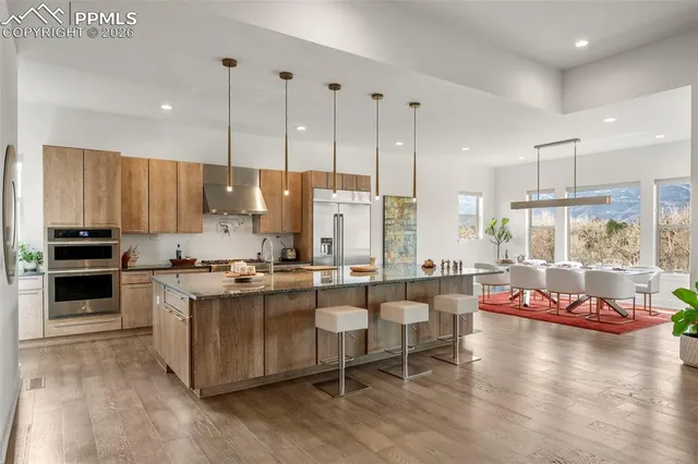 a kitchen with stainless steel appliances kitchen island granite countertop a stove and a view of living room with furniture