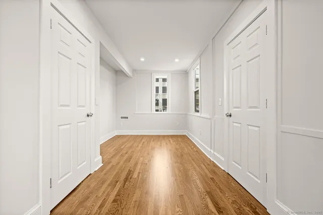 a view of a hallway with wooden floor and closet