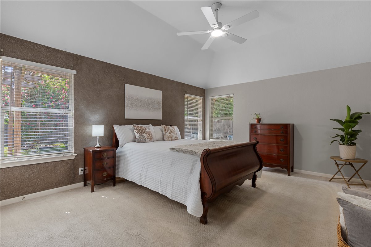 9012 Meacham Way Austin, TX 78749 - Photo 16 of 34 Vaulted ceiling with a ceiling fan, dual windows with horizontal blinds, textured accent wall, and carpeting