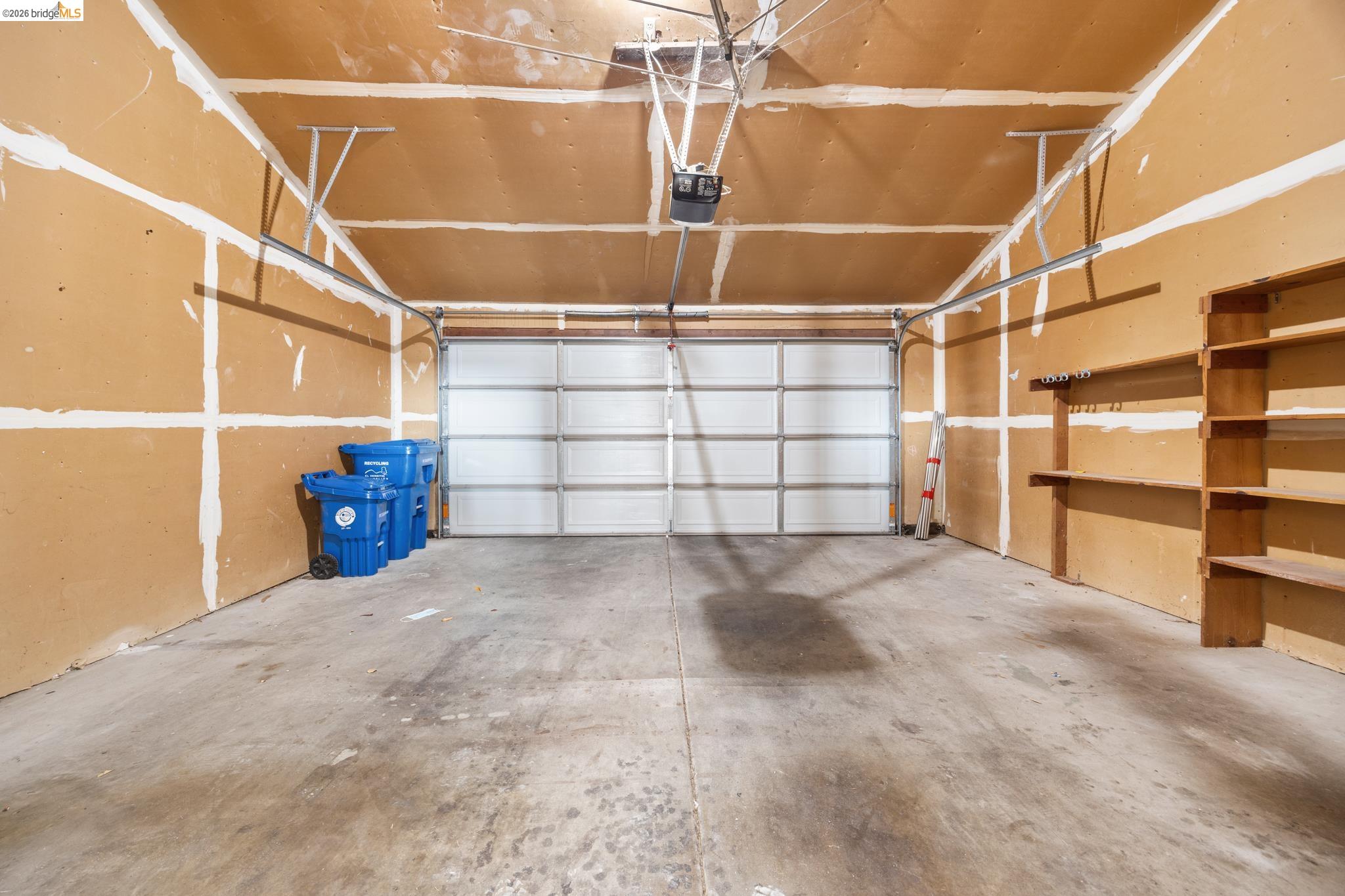 201 Vista Heights Road El Cerrito, CA 94530 - Photo 25 of 32 Garage featuring a sectional overhead door, concrete flooring, built-in shelving, and an automatic opener system