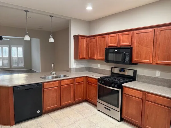 a kitchen with stainless steel appliances granite countertop wooden cabinets a stove a sink and a microwave