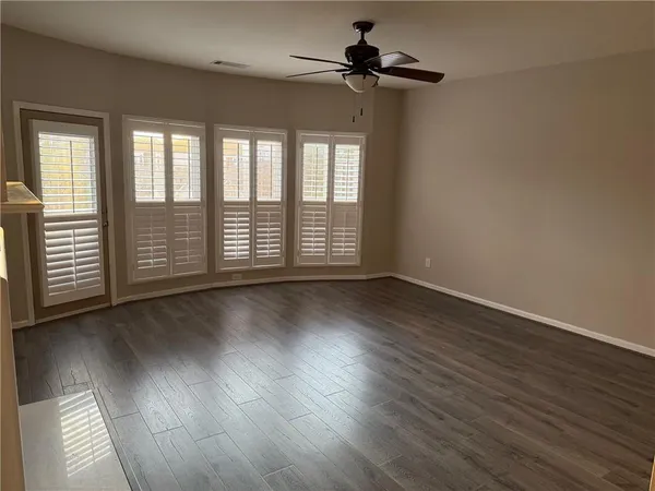 an empty room with wooden floor and windows