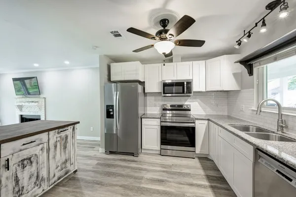 a view of a kitchen with kitchen island a counter top space stainless steel appliances and cabinets
