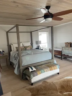 a bedroom with a bed a ceiling fan and a dresser