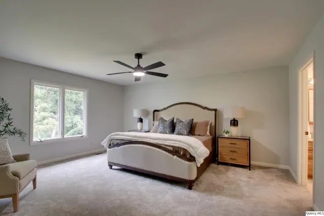 a bedroom with a bed a chandelier and a window