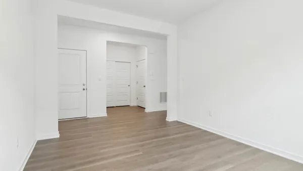 a view of an empty room with wooden floor and closet