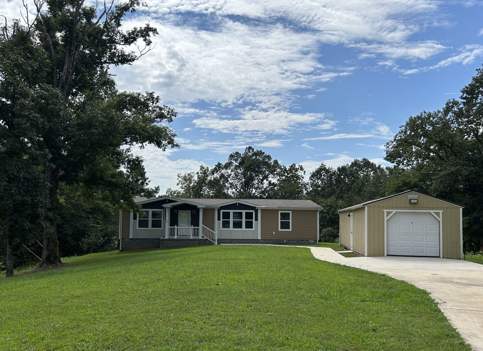 a front view of a house with a garden and trees