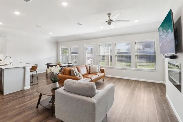 a living room with furniture a flat screen tv and wooden floor