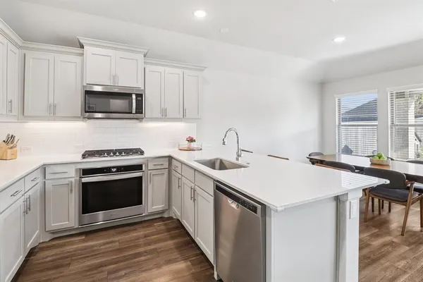 a kitchen with stainless steel appliances a stove microwave and sink