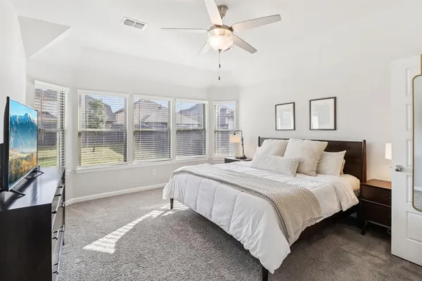 a bedroom with a large bed and a flat tv screen on dresser