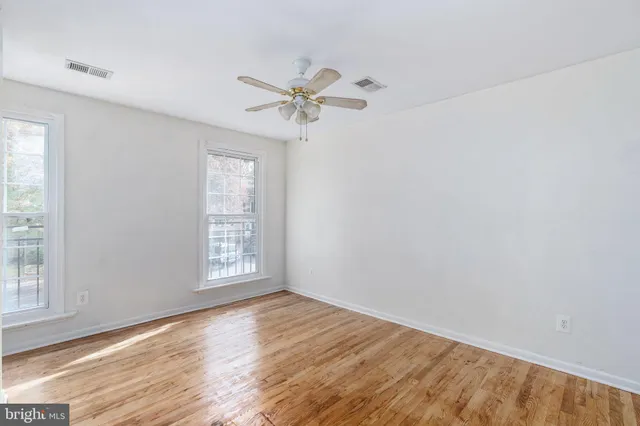 a view of empty room with wooden floor and fan
