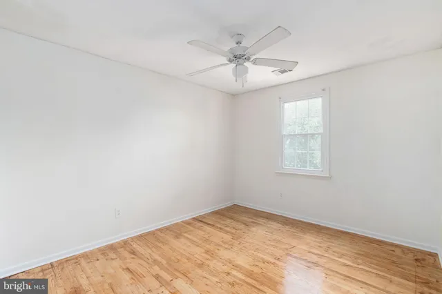 an empty room with a window and ceiling fan
