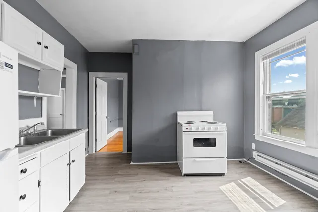 a kitchen with stainless steel appliances white cabinets and wooden floor