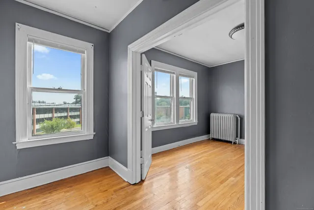 a view of an empty room with a window and wooden floor
