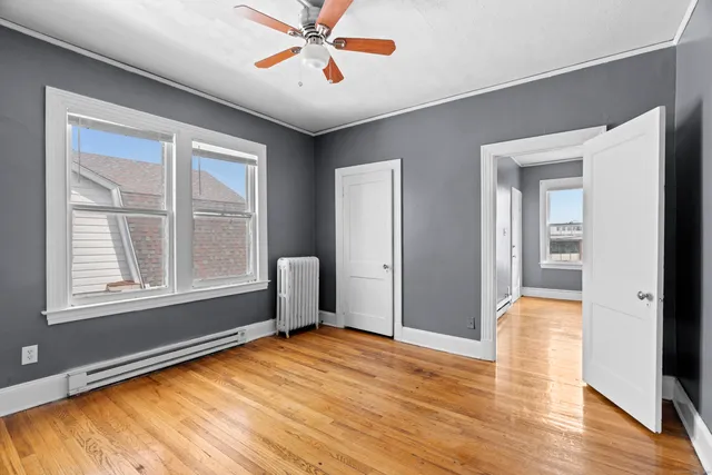 a view of empty room with wooden floor and fan