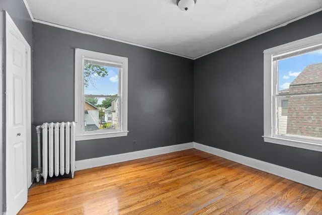 a view of empty room with window and wooden floor