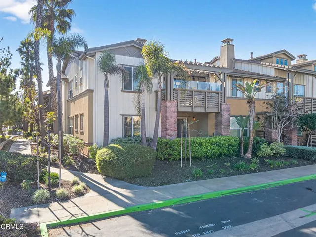 a front view of a residential apartment building with a yard and potted plants