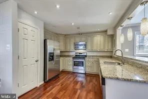 a kitchen with kitchen island granite countertop a sink cabinets and stainless steel appliances