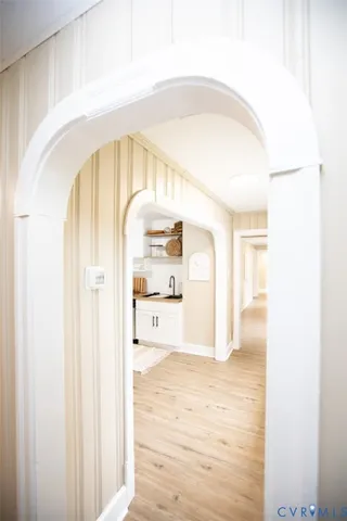 a kitchen with stainless steel appliances a stove a sink a refrigerator and white cabinets with wooden floor