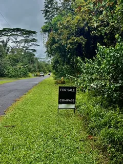 a sign that is sitting in the grass next to a road
