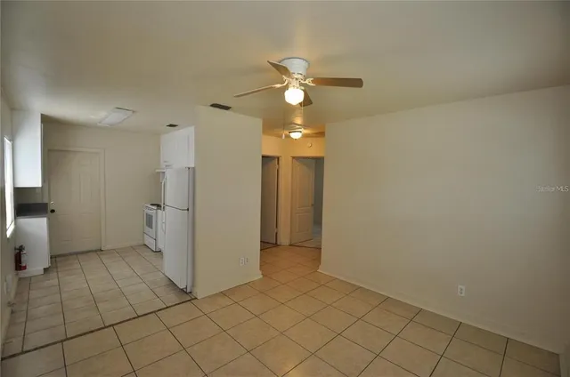 a view of a livingroom with a chandelier fan and kitchen view