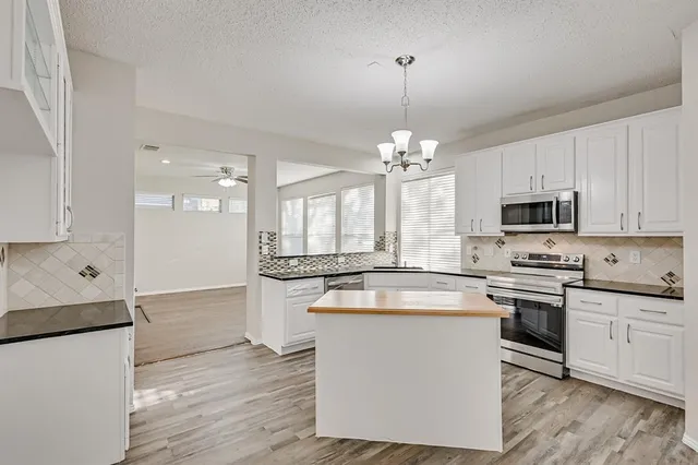a kitchen with stainless steel appliances granite countertop a stove oven and a white refrigerator