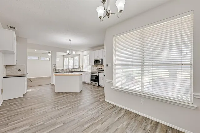 a view of kitchen with microwave a refrigerator and cabinets
