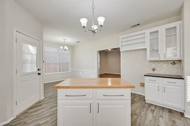 a kitchen with stainless steel appliances granite countertop a sink a stove and white cabinets with wooden floor