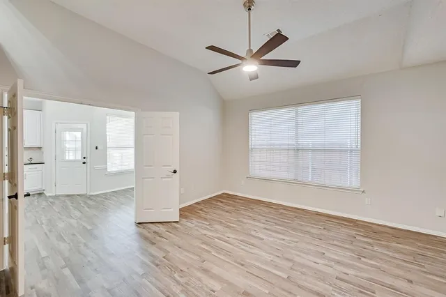an empty room with wooden floor cabinet and windows