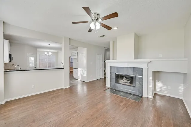 an empty room with wooden floor a fireplace and windows