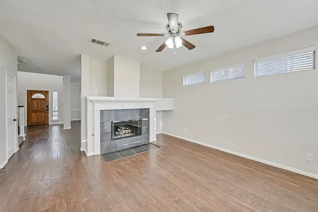 a view of a livingroom with a fireplace a ceiling fan and wooden floor