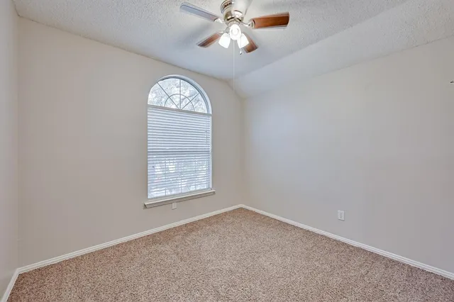 an empty room with a window and a chandelier fan