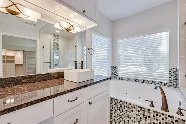 a bathroom with a granite countertop sink and a bathtub