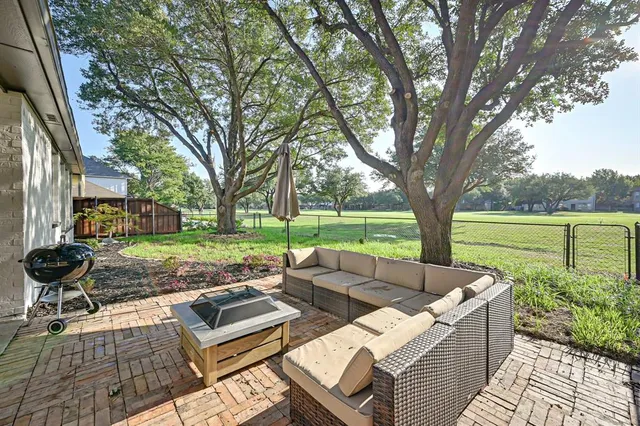 a view of a backyard with couches plants and large trees