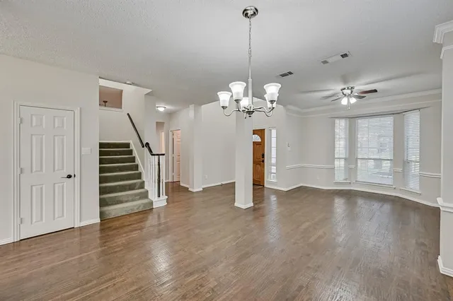 a view of an empty room with wooden floor staircase and a kitchen