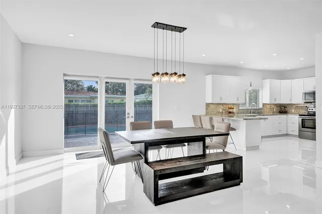 a kitchen with stainless steel appliances kitchen island granite countertop a stove a sink a refrigerator and white cabinets with wooden floor