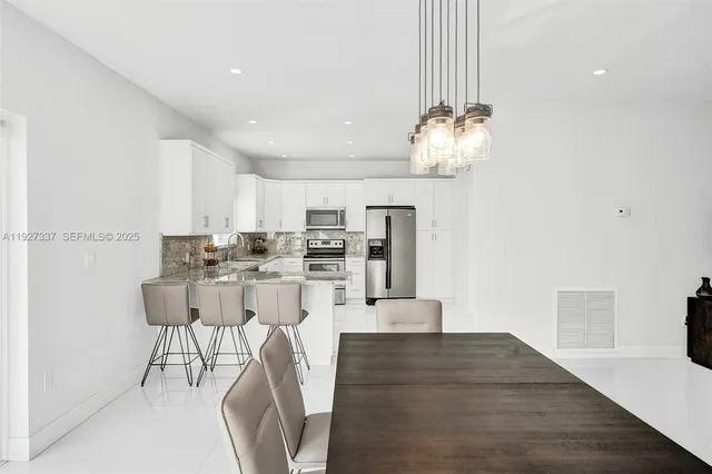 a kitchen with stainless steel appliances granite countertop a stove a sink a refrigerator and white cabinets