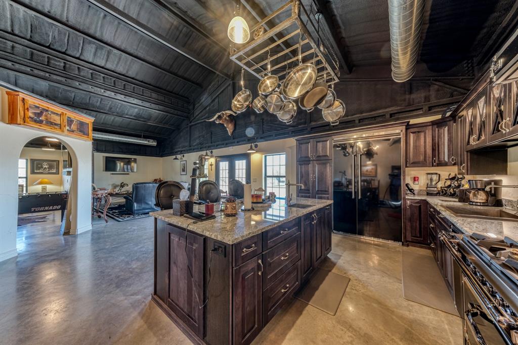 2337 Walsh Road Olney, TX 76374 - Photo 26 of 38 Spacious kitchen featuring a large central island with a light-toned countertop, dark wood cabinetry, and stainless steel appliances