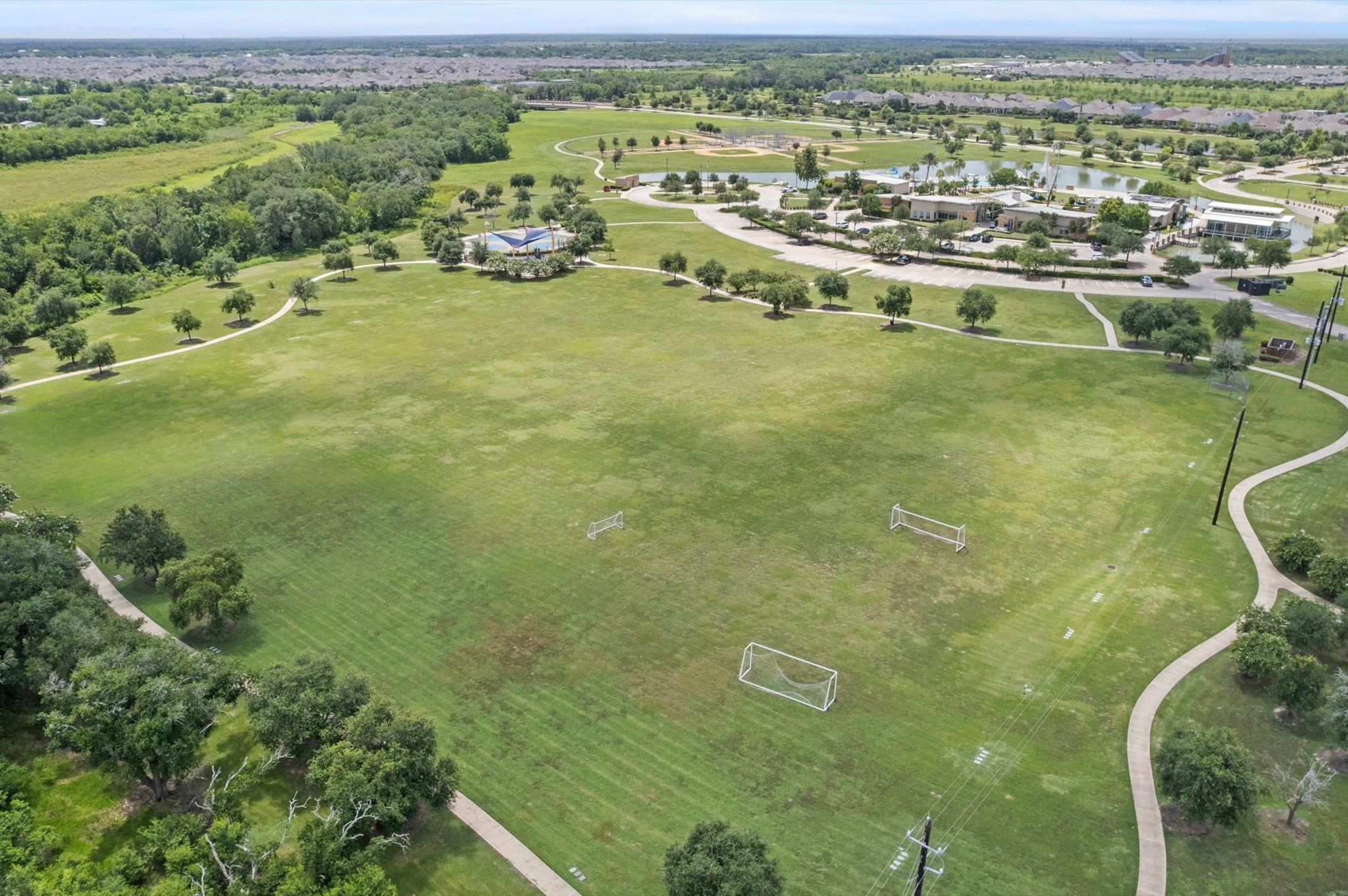 3510 Whitman Drive Rosharon, TX 77583 - Photo 22 of 25 Expansive green park with walking paths and soccer fields, surrounded by lush trees. Nearby community buildings and a pond offer recreational opportunities, ideal for families and outdoor enthusiasts.