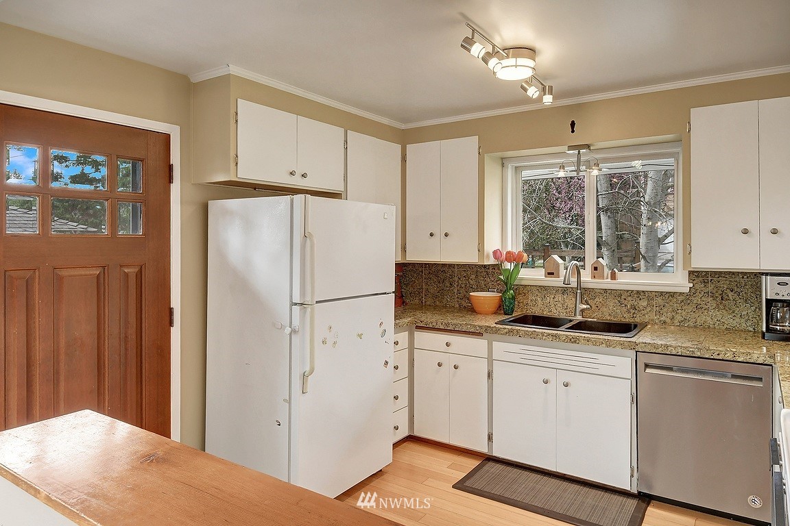 8202 37th Avenue Southwest Seattle, WA 98126 - Photo 8 of 27 a kitchen with granite countertop a refrigerator a sink stainless steel appliances white cabinets and a window